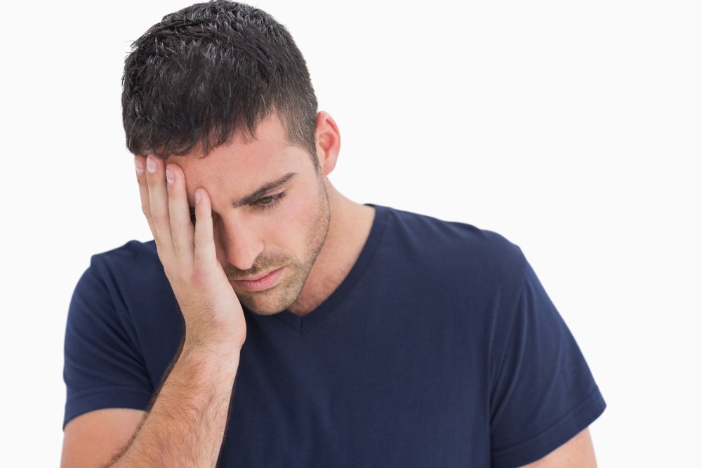 Unhappy man with head in hand on white background