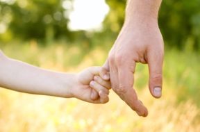 trust family hands of child son and father on wheat field nature