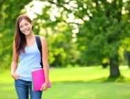 Student girl portrait holding books wearing backpack outdoor in