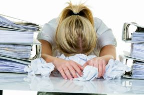 a young woman desperately in office between many file folders an