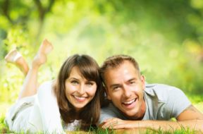 Happy Smiling Couple Together Relaxing on Green Grass. Park. You