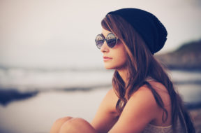 Fashion portrait of young hipster woman with hat and sunglasses